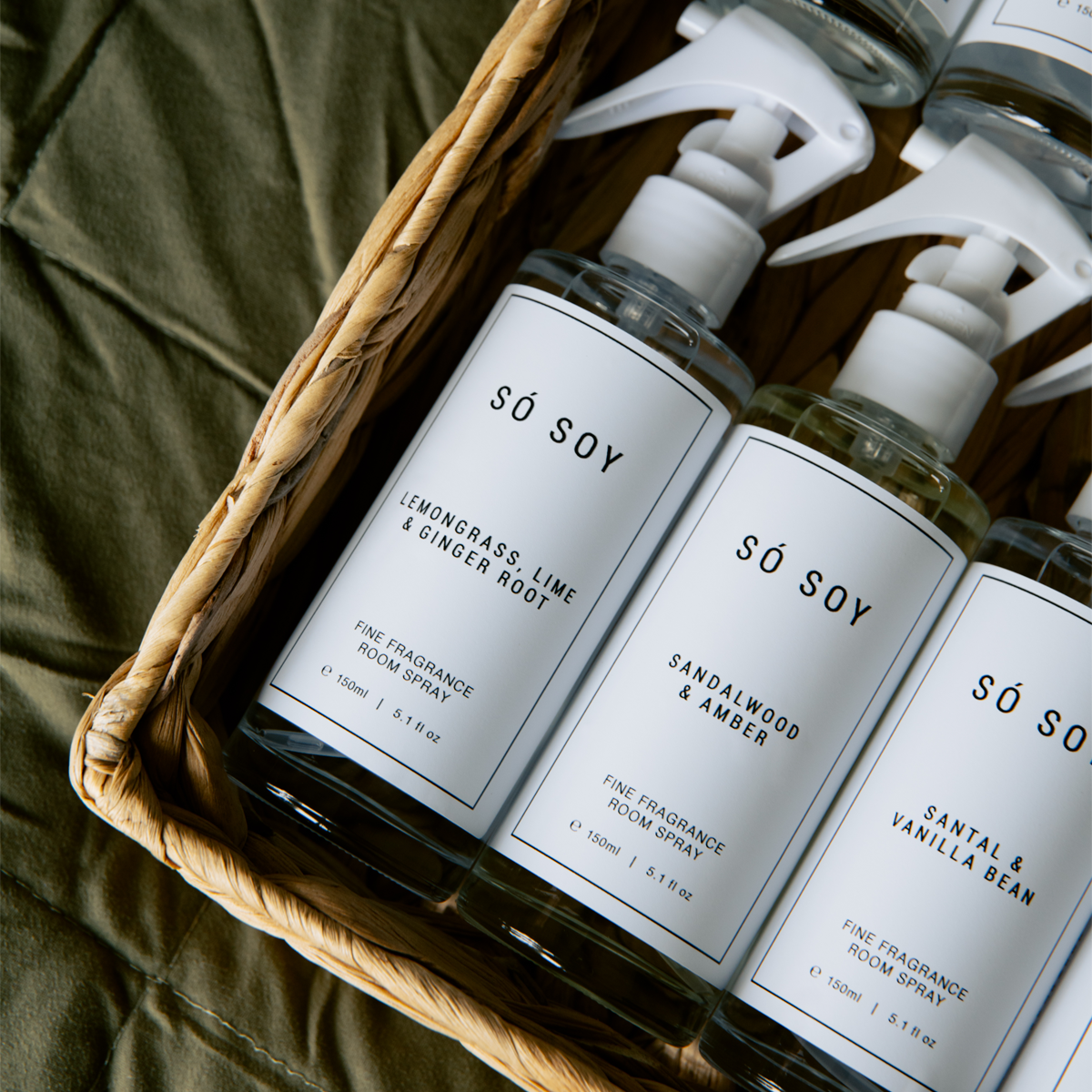 Só Soy room spray bottles in a basket with labels on a green fabric background